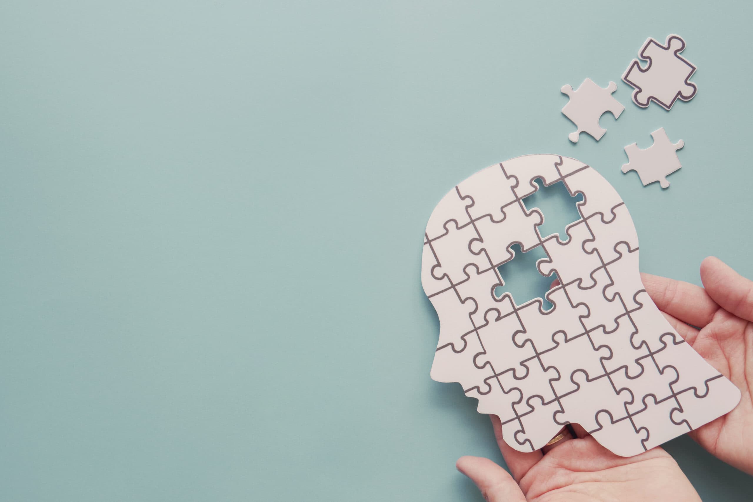 Hands holding a paper brain puzzle, representing EMDR and brain neuroplasticity