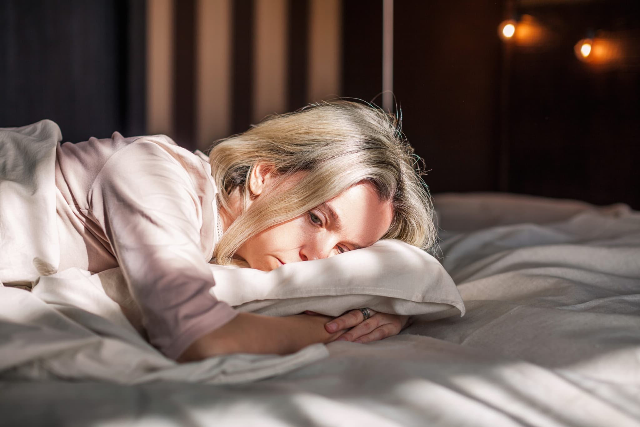 Woman lying in bed and looking like she could be depressed.
