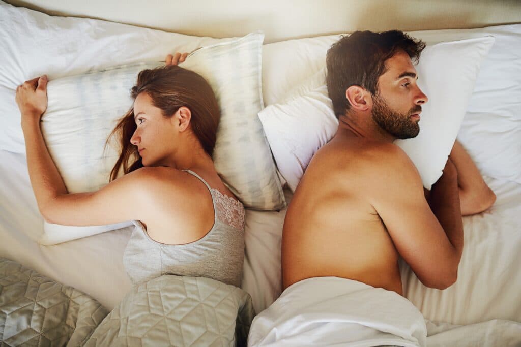 Two adults lying apart in bed