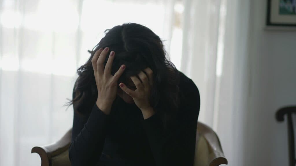 A person seated with their head in their hands