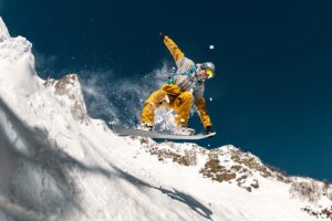 professional,male,snowboarder,jumps,in,powder,snow,from,kicker,against