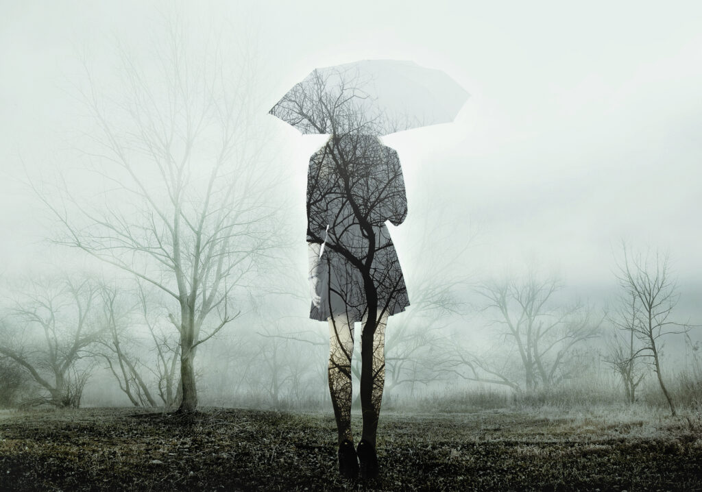 woman,with,umbrella,standing,on,the,field,with,trees.,the
