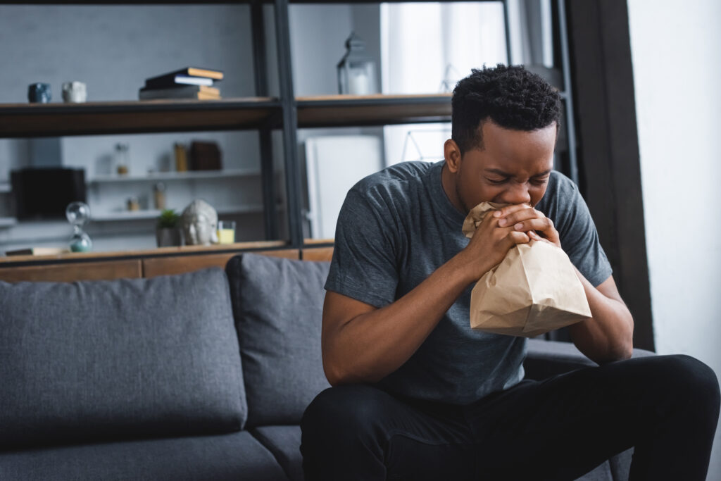 stressed,african,american,man,breathing,with,paper,bag,while,having