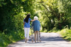 female,caregiver,and,senior,woman,with,walker,on,walk,in